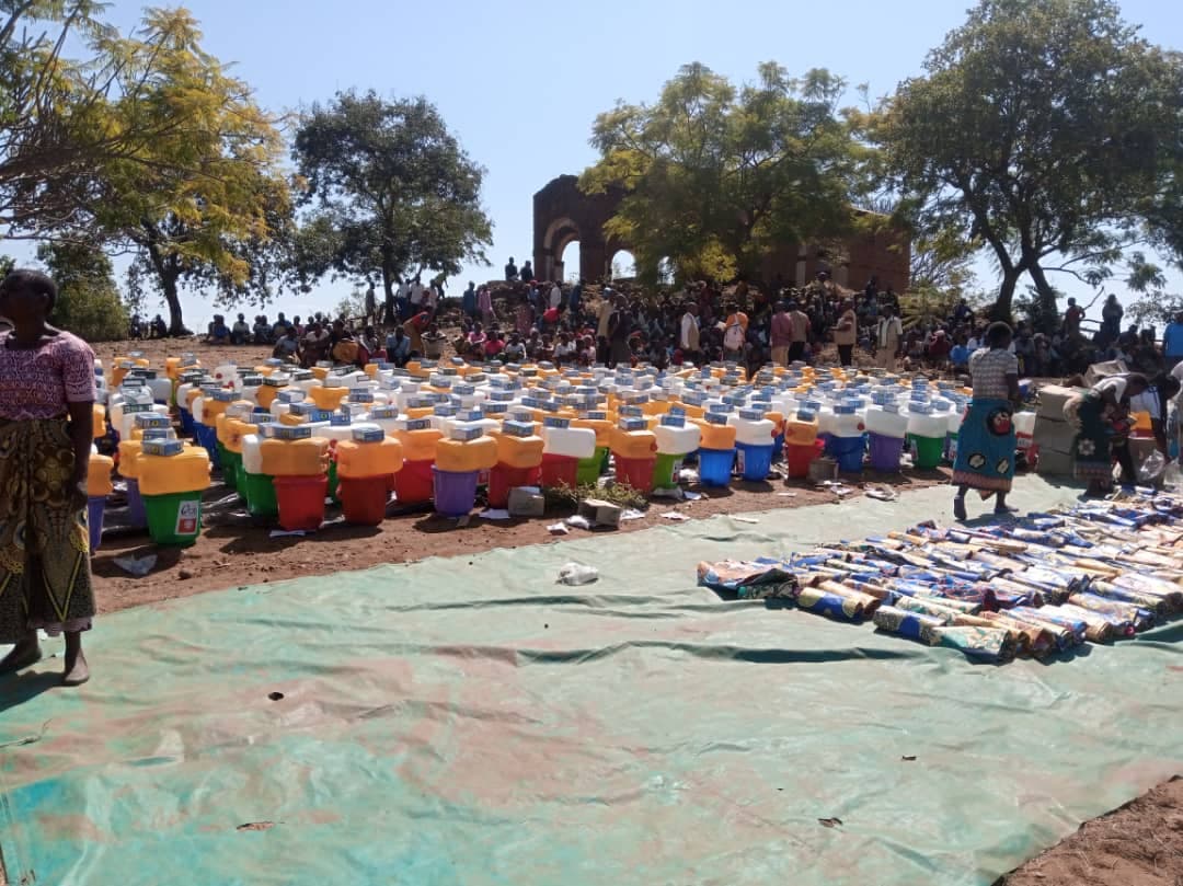 Community members receiving shelter and WASH kits including buckets, tarpaulins, and hand tools